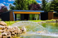 Maison moderne avec étang et fontaine.