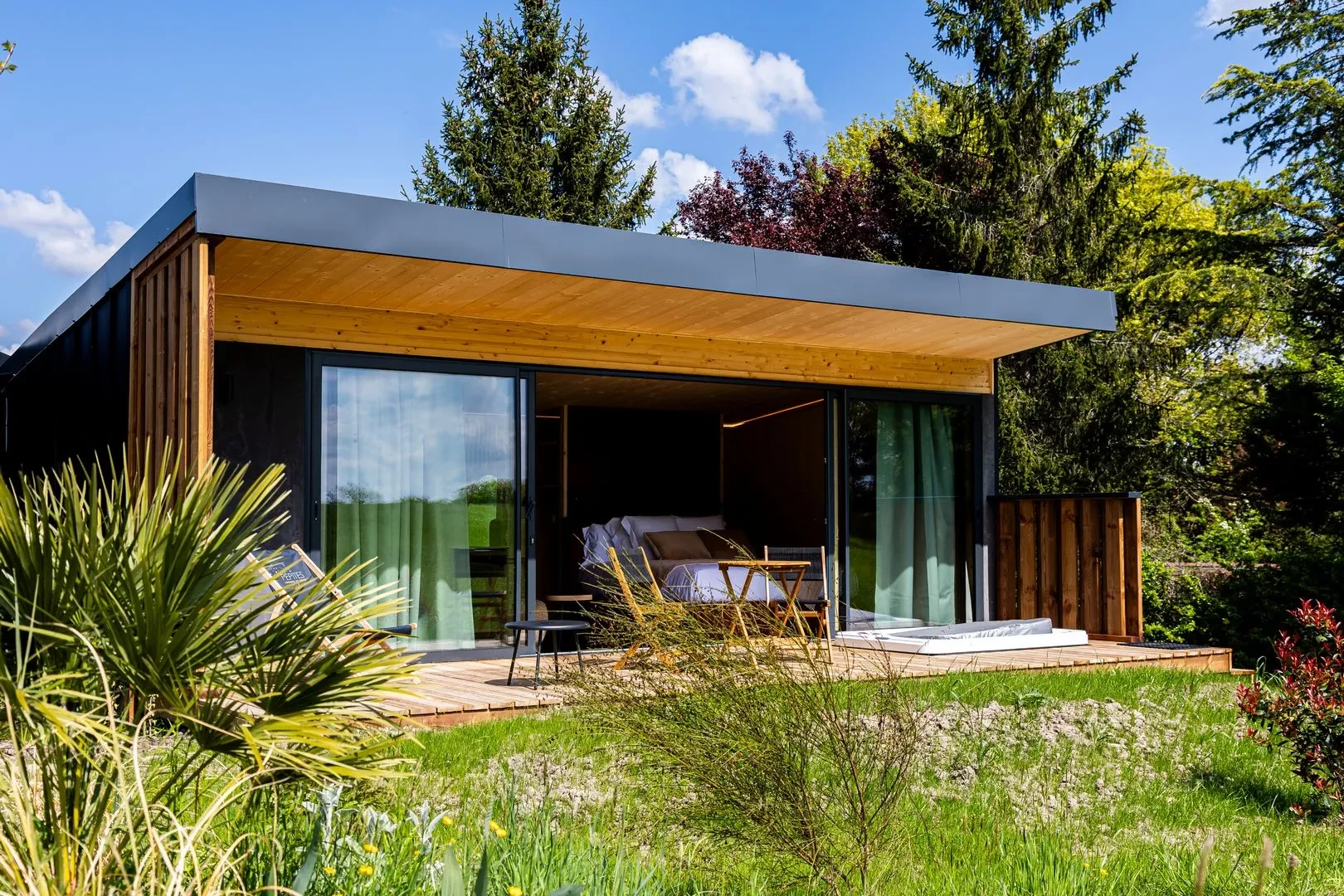 Chalet moderne en bois avec terrasse, entouré de verdure.