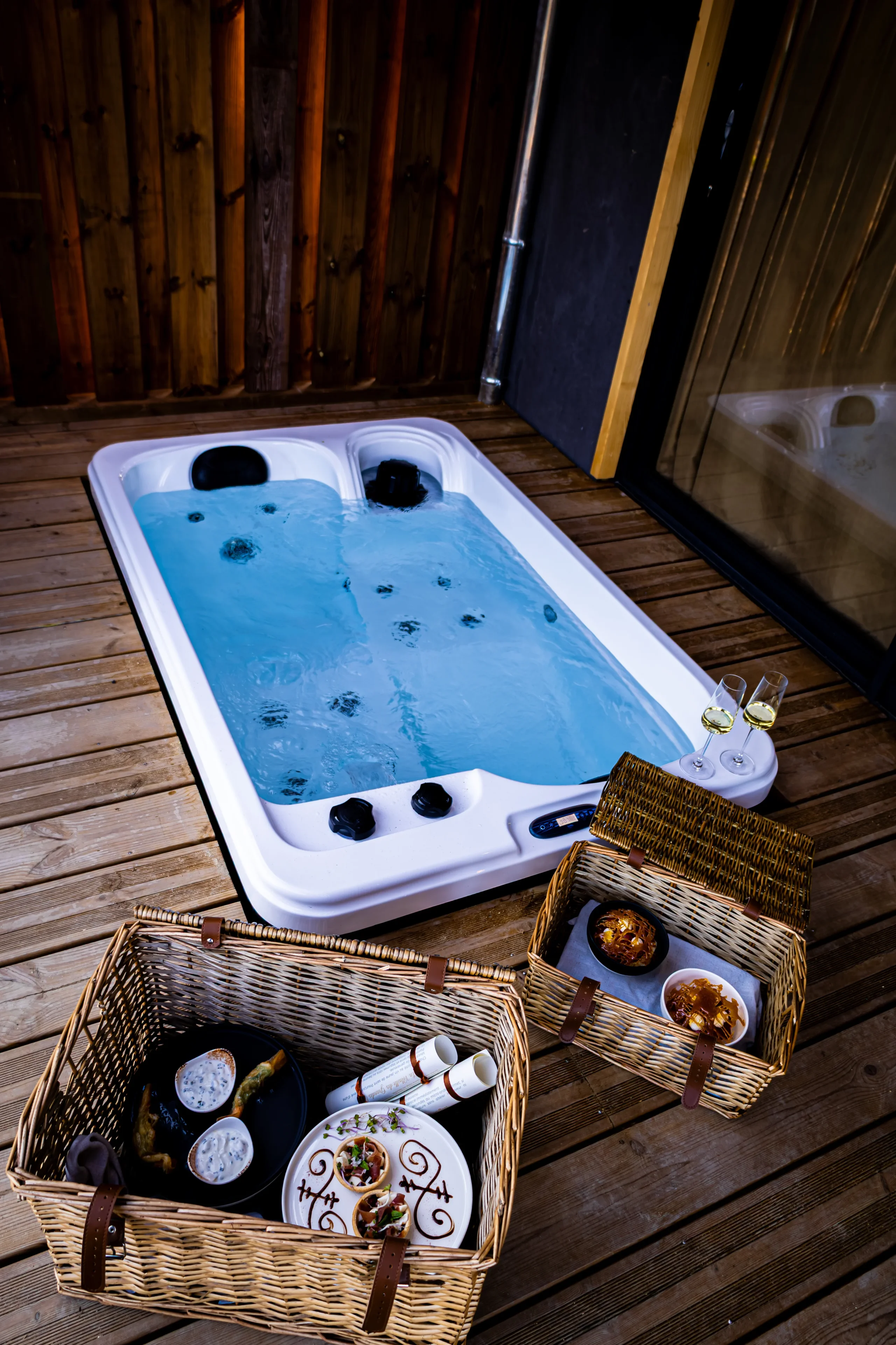 Jacuzzi extérieur avec vin blanc et panier gastronomique.