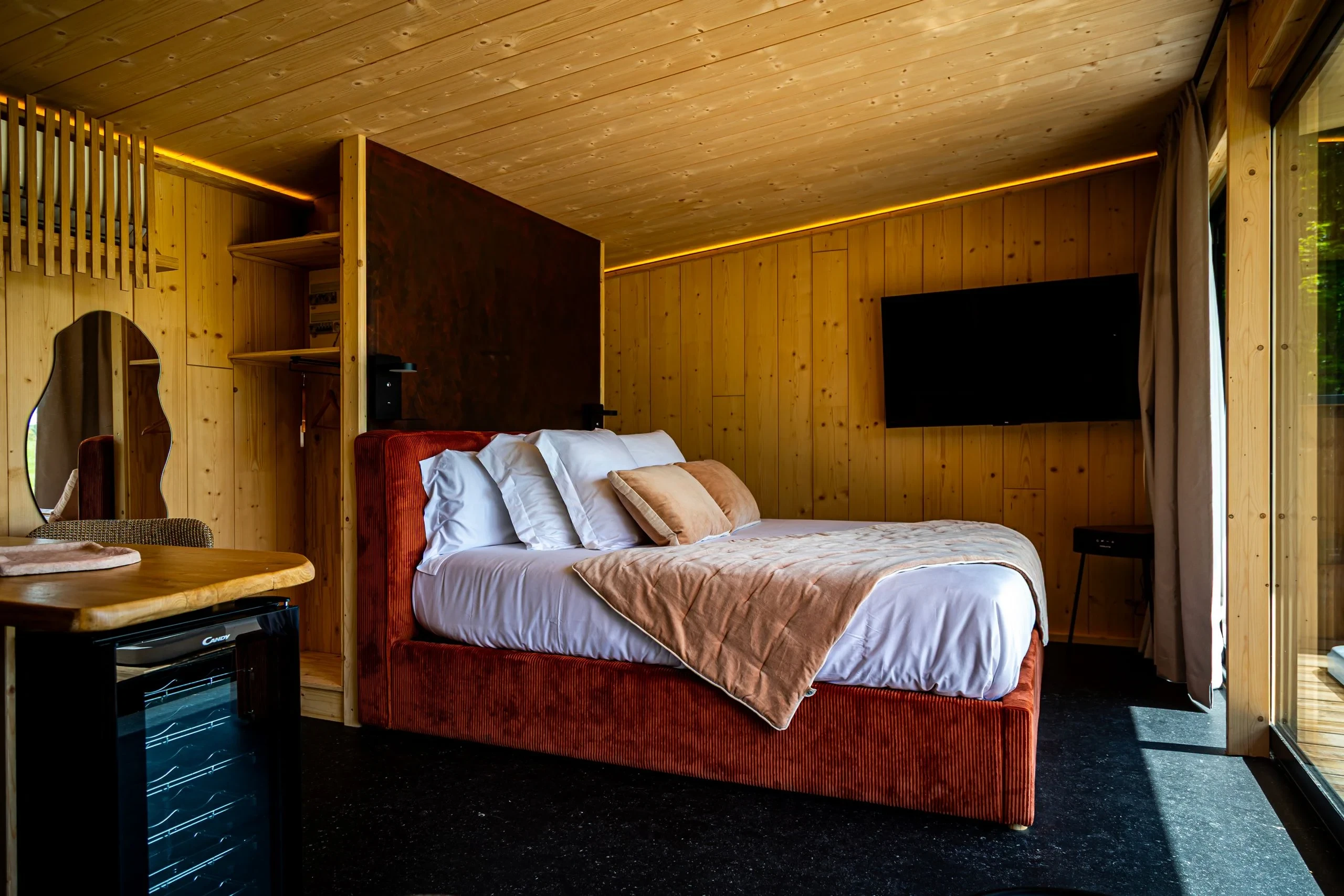 Chambre en bois avec lit double et télévision murale.