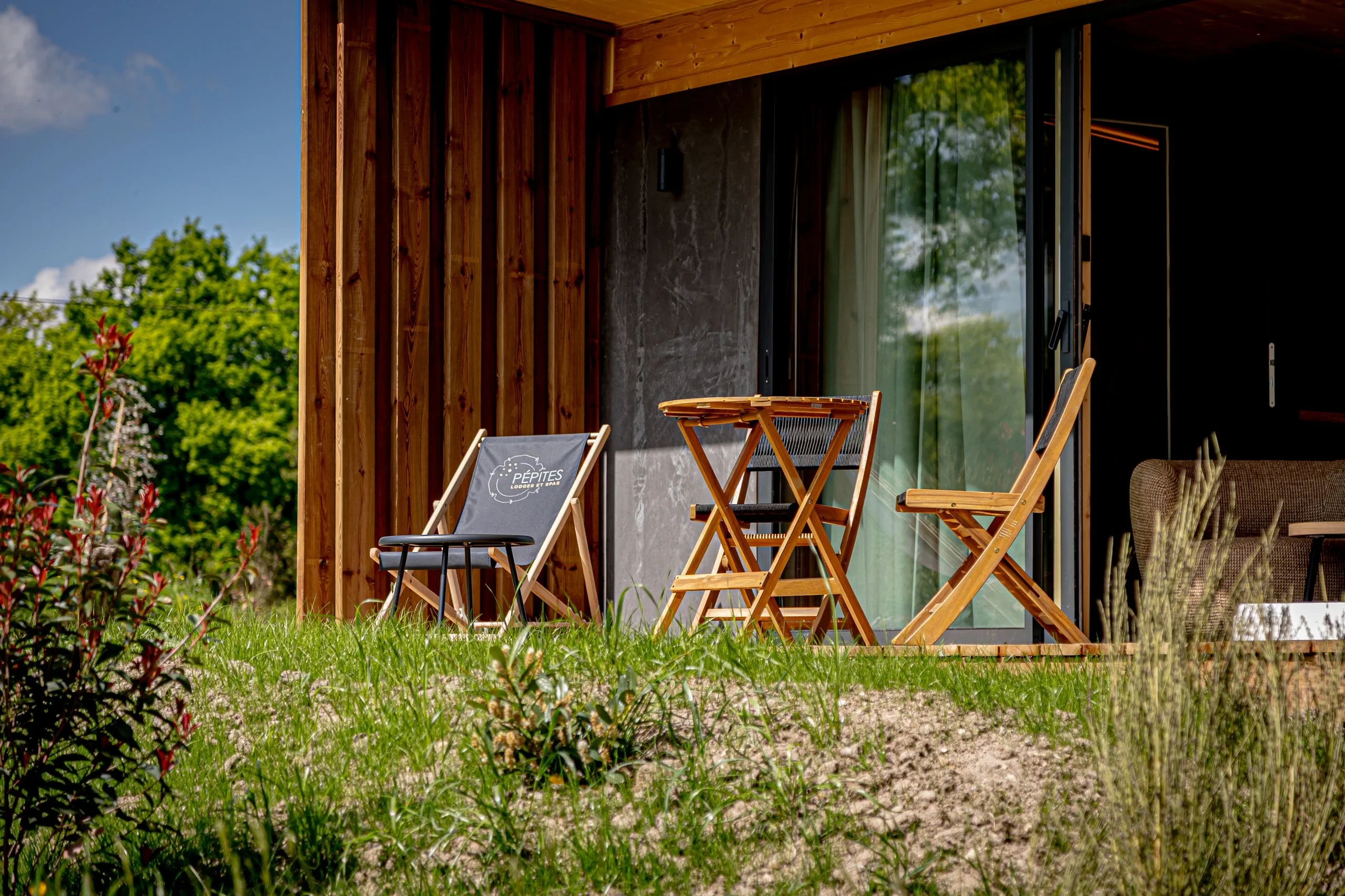 Chaises en bois sur terrasse près de forêt verdoyante.